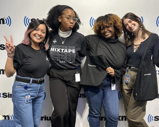Four female SiriusXM employees pose together happily